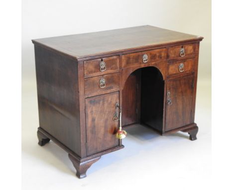 A George I style walnut and crossbanded pedestal desk, containing an arrangement of short drawers and cupboards, around a cen