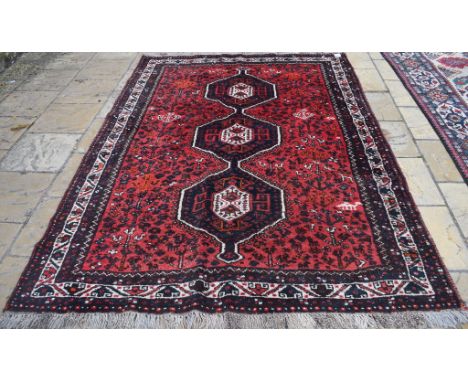 A Persian Qashqai carpet, decorated three central medallions on a red ground, within a multi border, 287 x 200 cm 