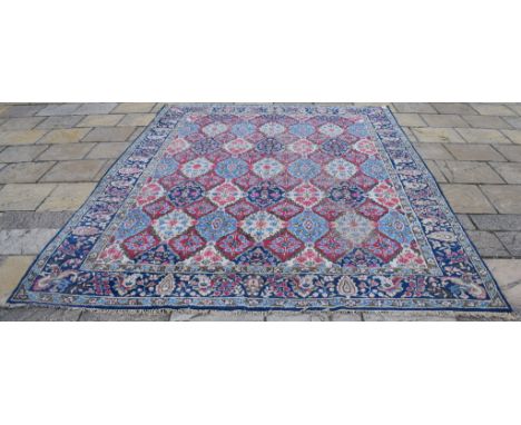 A Persian Kirman carpet, decorated floral panels on an ivory ground, within a multi border, 365 x 258 cm