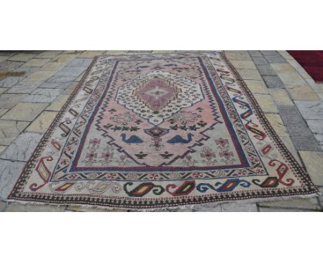 A Turkish Milas carpet, decorated animal and foliate shapes on a cream ground, within a multi border, 367 x 238 cm