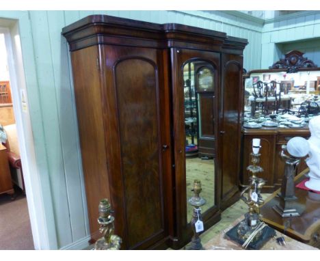 Mid 19th Century mahogany breakfront wardrobe having central mirror door enclosing trays and drawers flanked by two arched pa