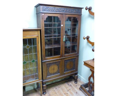 1920's/30's oak cabinet bookcase having two glazed panel doors above two carved panel doors on turned legs