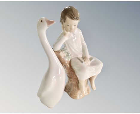 A Lladro figure of a boy sat on a tree stump and a further Lladro goose.