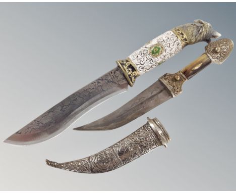 A large hunting knife with etched wolf decoration and wolf head handle together with an Eastern curved knife in white metal s