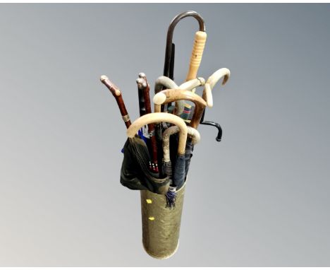 A brass embossed stick stand containing a collection of umbrellas.