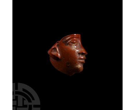 Ptolemaic Period, circa 332-32 B.C. A red glass insert of a profile face with remains of a pharaonic crown to the forehead. C