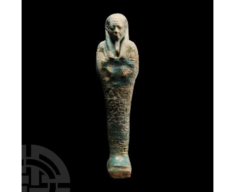 7th-1st century B.C. A glazed composition shabti with square base and plain dorsal pillar, tripartite wig and false beard, ar