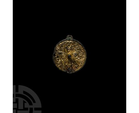 Circa 9th century A.D. A large gilt copper-alloy pin head of discoid form, displaying a central knop and stylised chip-carved