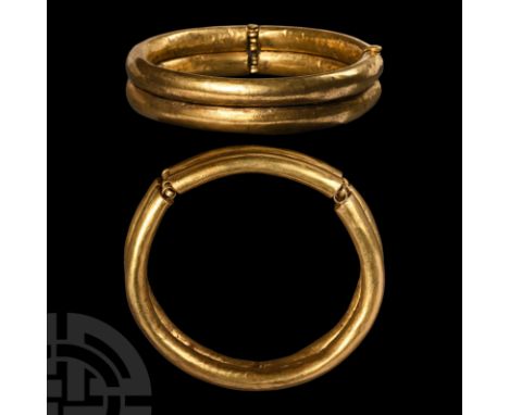 2nd century B.C. A substantial gold bangle with hinged clasp, composed of two conjoined oval-section hoops, gusseted loops to