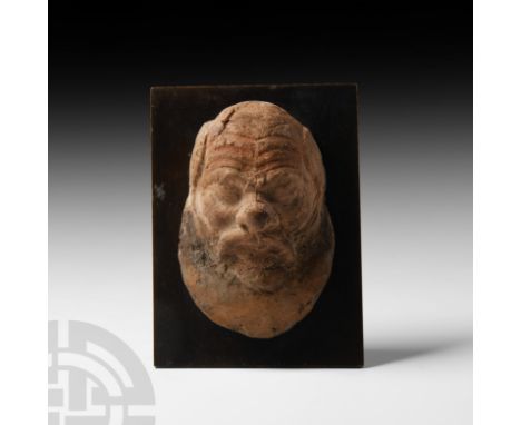 6th-5th century B.C. A terracotta head of a satyr (probably Silenus) with furrowed brow, prominent moustache and crescent bea