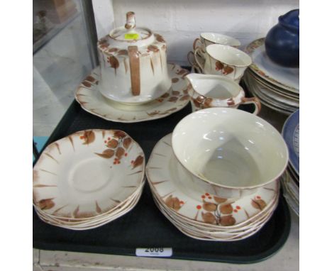 A part tea service, on cream ground decorated with red berries and brown leaves, comprising four cups and saucers, side plate