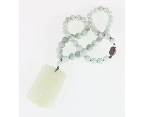 Carved jade pendant of rectangular shape on green hardstone necklace with sterling silver clasp.