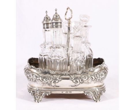 Victorian silver cruet stand of boat form with embossed decoration and later handle containing five glass cruet bottles, 21cm