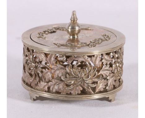 A 19th century Chinese silver box and cover of circular section, the body carved and pierced with chrysanthemum and leafage, 