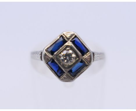 An 18 ct white gold Deco style diamond and sapphire ring. Ring size K/L. 2.9 grammes total weight.