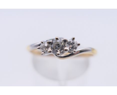 An 18 ct gold three stone diamond ring. Ring size Q/R. 2.4 grammes total weight.