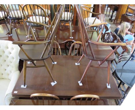 An Ercol medium elm dining suite comprising draw leaf dining table together with six arched topped spindle back dining chairs