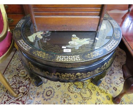 A contemporary Chinese lacquered circular topped coffee table having relief and gilt decoration depicting stylised figures an