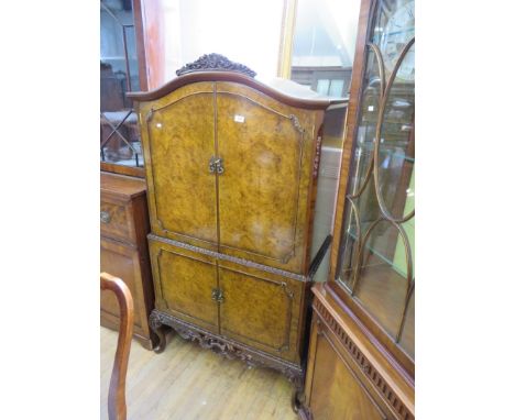 A good quality mid Century burr walnut veneered twin door cocktail cabinet, the twin panelled doors enclosing glass shelf   C