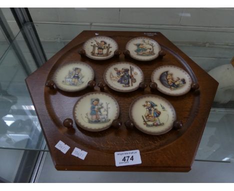 A collection of seven M J Hummel/Goebal miniature wall plates and accompanying wooden rack.