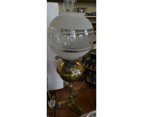 A late 19th Century oil lamp with frosted glass shade and chimney, over a brass font and tapering column to a three footed ba