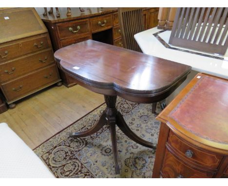 A reproduction mahogany fold top card/tea table on turned pedestal and quatra base, with brass paw feet