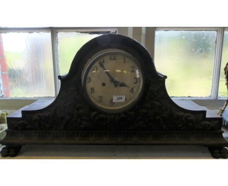 A very large oak cased mantel clock decorated with Gothic style carving and raised on paw feet
