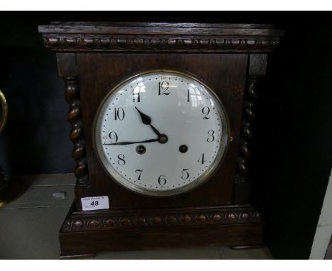 An early 20th Century oak cased mantel clock with barley twist side supports.