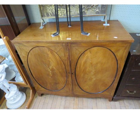 A 19th Century mahogany two door cupboard the oval panelled doors opening to reveal a shelved interior, raised on bracket fee