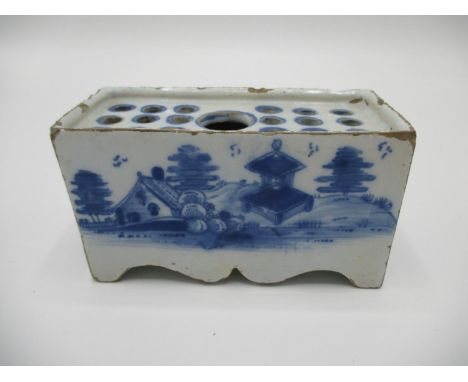 A late 18th century Dutch Delft flower brick with a large central hole flanked by eighteen smaller holes, on shaped bracket f