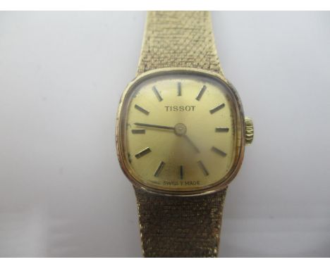 A Tissot ladies 9ct gold manual wind wristwatch having a gilt dial with baton markers, integral fitted 9ct gold bracelet and 