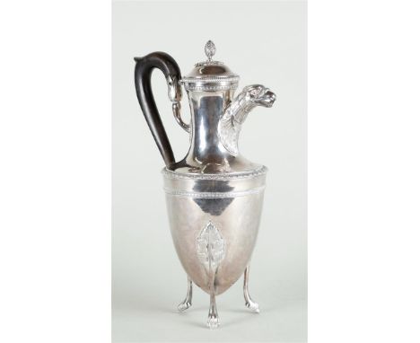 A silver jug on three high legs, with an acorn-shaped knob on the lid and with rich leaf decoration and pearl edge, the spout