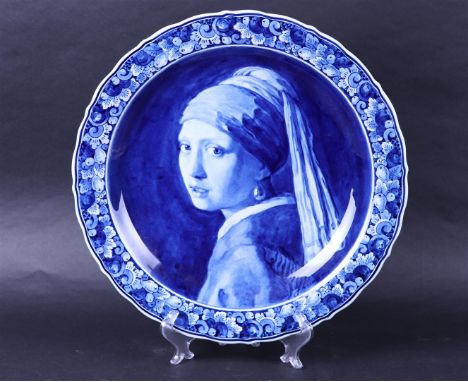 A large earthenware wall dish with an image after Vermeer 'Girl with a pearl earring'. Delft porcelain bottle.Diam. 40 cm.