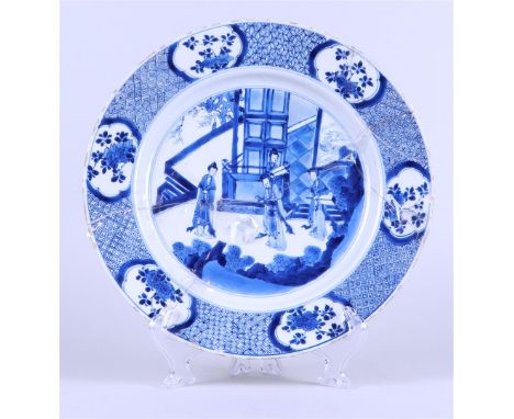 A large porcelain dish decorated with ladies-in-waiting, marked on the back. China, Kangxi. Restoration object.Diam. 32 cm.