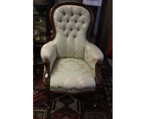 A late Victorian mahogany deep button backed Gentleman's armchair with blue patterned upholstery with turned legs