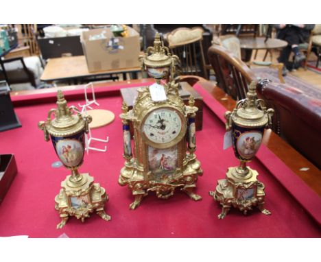 A gilt metal mantle clock with garniture, transfer printed decoration to ceramic inserts, clock having enamelled dial with Ar