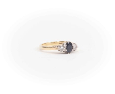  A sapphire and diamond ring set to the centre with an oval sapphire, two diamonds set either side, 18ct gold setting, size M