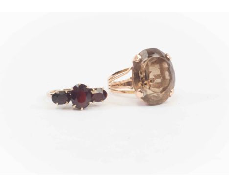 Two 9ct gold rings, comprising a large smoky quartz ring, with open shoulders, size N, along with a 9ct gold and garnet three