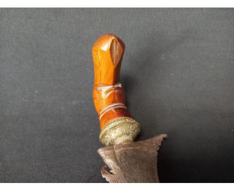 A 20th century Indonesian ceremonial Kris dagger  with a carved hardwood handle and sheath and a folded and textured steel bl