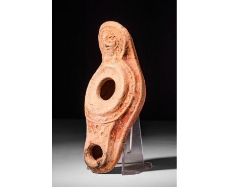 Ca. AD 400 - 500.A Levantine terracotta oil lamp featuring a pointed oval body and a prominent decorated handle. The vessel d