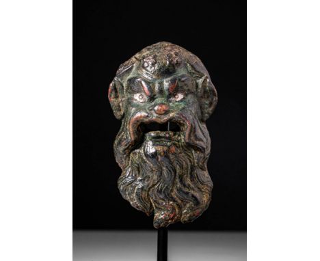 Ca. AD 100 - 300 .A fine cast-bronze applique depicting the head of a bearded deity, most likely Silenus. The face is charact
