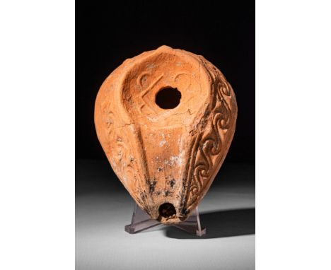 Ca. AD 300 - 400.A Levantine terracotta oil lamp featuring a pointed oval body and a prominent conical handle. The lamp displ