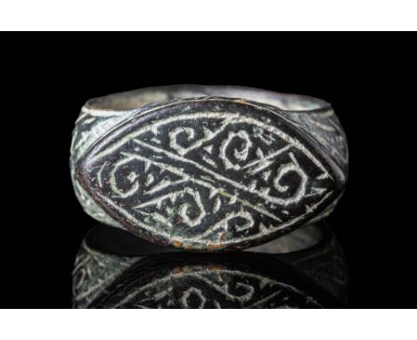 Ca. AD 1100 - 1300.A Medieval bronze ring with round hooped D section connecting to the almond shape bezel. The bezel is engr