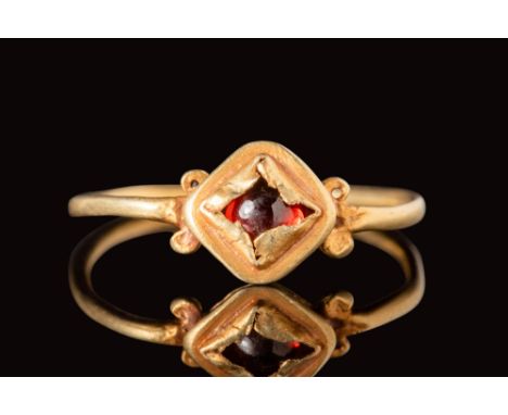 Ca. AD 1400 - 1600.A Renaissance gold finger ring with a square bezel, crimped to secure a round garnet cabochon. The shoulde
