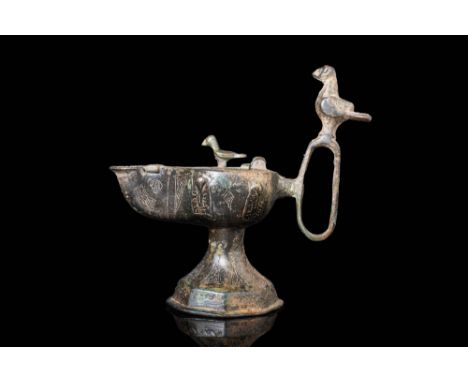 Ca. AD 1000 - 1200.A Seljuk bronze oil lamp of typical form, with bird mounted to handle and engraved with inscriptions to th