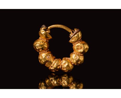 Late Period, Ca. 664 - 332 BC.An Egyptian gold earring composed of a round hoop formed with gold pellets and lines of granule