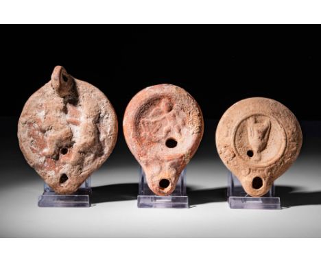 Ca. AD 100 - 300.An attractive collection of three pottery Roman oil lamps. The first lamp, on the left, has a convex mould-m
