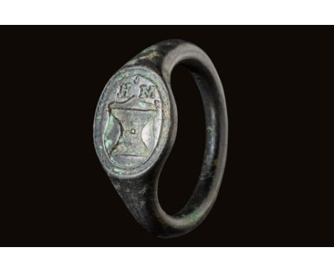 Ca. AD 1400 - 1600.A late medieval bronze merchant's ring with an oval bezel, depicting a shield surmounted by the initials H