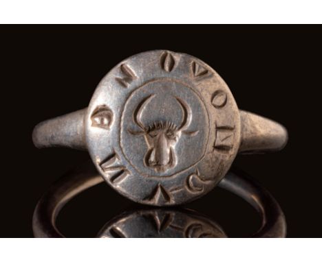 Ca. AD 1200 - 1400.A rare Byzantine silver ring with a round hoop connected to a circular bezel depicting a bull's head surro