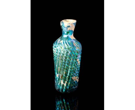 Ca. AD 900 - 1000.A beautiful Abbasid blue and green glass bottle. It is formed by a pattern molding process to create dozens